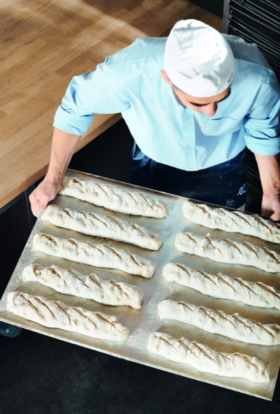 Bäcker mit Baguette am Backblech